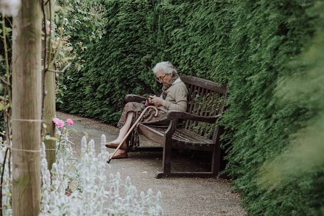 Starsza kobieta siedząca na ławce